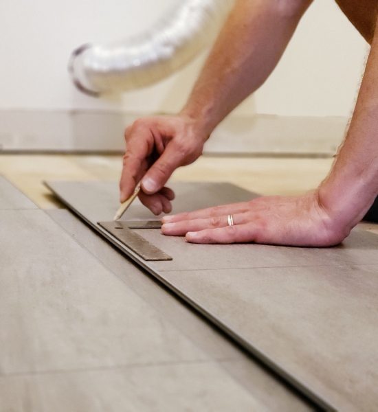 Man's hands holding flooring plank and measuring place to cut for floor installation home improvemen