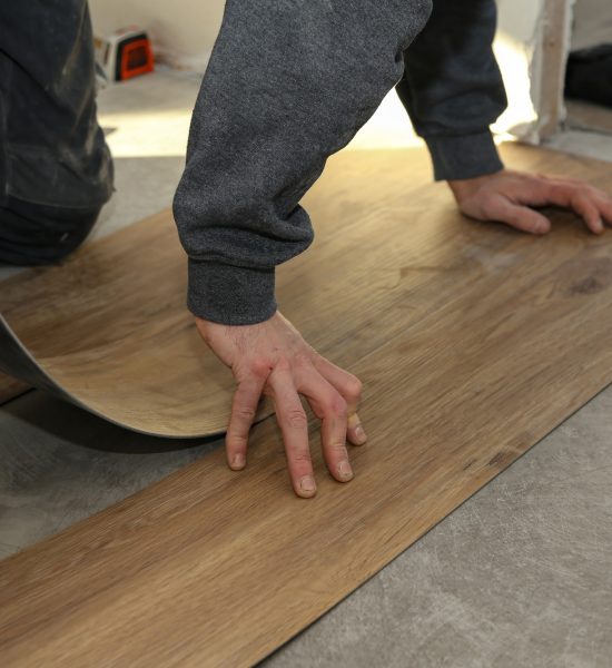 The worker installing new vinyl tile floor